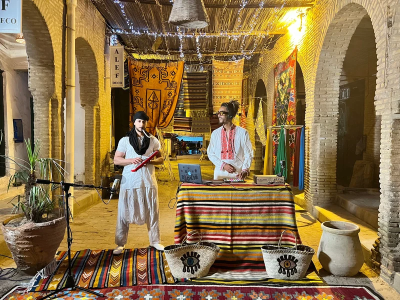 DJ JOK3R performing with another musician in a traditional courtyard
