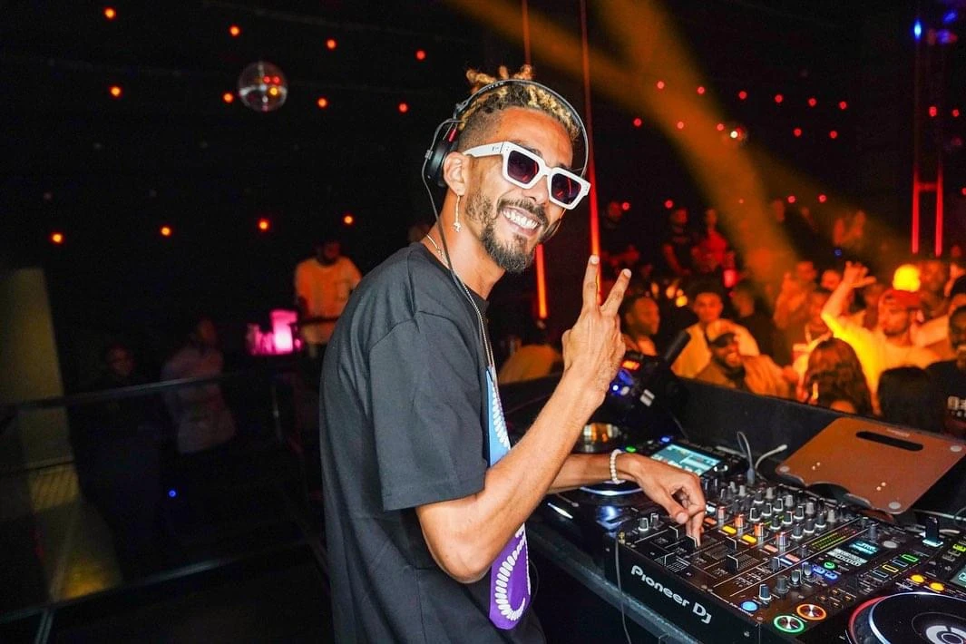 DJ JOK3R smiling behind the decks during a live performance