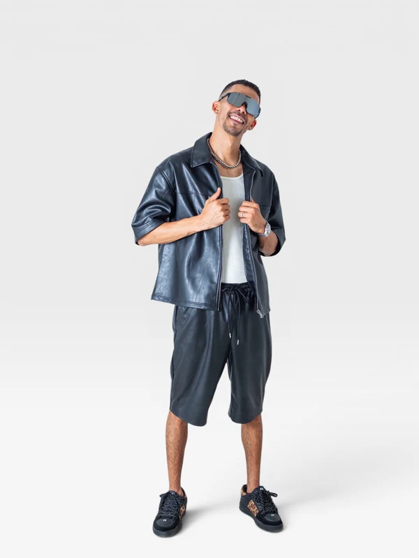 Full-length studio portrait of DJ JOK3R in sunglasses, a black shirt and shorts