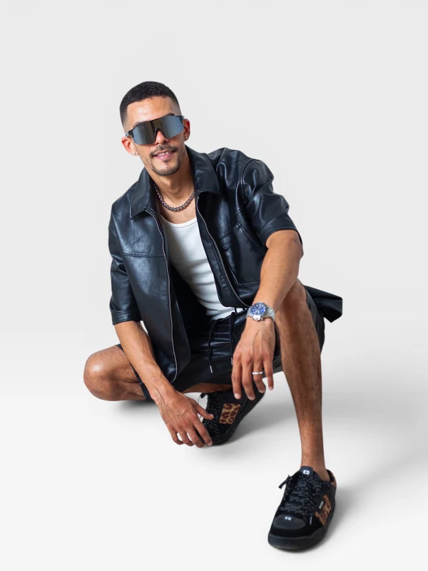 DJ JOK3R seated in a studio, wearing a black shirt and sunglasses
